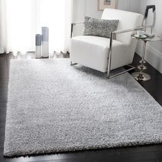 a white chair sitting on top of a wooden floor next to a rug and window