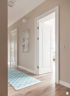 an empty hallway with two doors and a rug on the floor in front of it