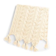 a white knitted blanket with tassels