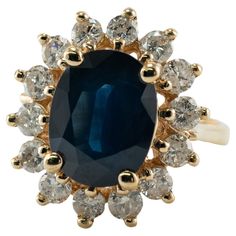 an oval shaped blue stone surrounded by white and yellow diamonds in a gold ring with two rows of smaller round stones surrounding it