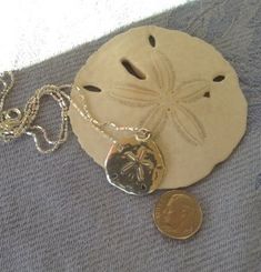 Timeless sterling silver diamond cut necklace with a medium to large-sized (please see pictures with dime) sand dollar charm attached to a sterling 16 inch chain. This is not huge but big enough to make a statement and great for everyday wear. Represents beautiful legend of the sand dollar. Please select 16 or 18 inch chain before adding to cart. Simple but elegant and perfect for any time. Silver Engraved Necklace For Beach, Engraved Pendant Necklace For Beach, Silver Necklace For Beach, Silver Round Beach Necklace, Silver Coastal Jewelry Gift, Coastal Style Silver Jewelry For Gifts, Coastal Style Silver Jewelry Gift, Beach Pendant Jewelry With Engraving, Beach Engraved Pendant Jewelry