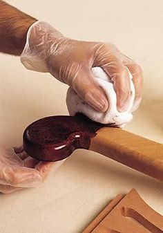 a person in white gloves is holding a piece of meat on a wooden stick and cutting it into smaller pieces