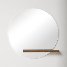 a round mirror hanging on the wall next to a wooden stick