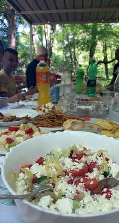 a bowl of food on a table with people sitting at the table in the background