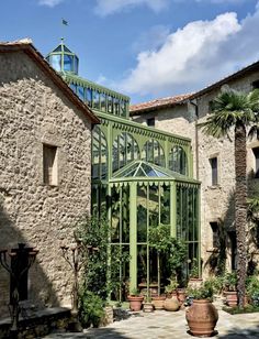 an old building with a green glass door and windows on the outside, surrounded by potted plants