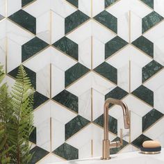 a white sink sitting under a faucet next to a green plant