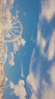 a ferris wheel is shown against a blue sky with white clouds in the foreground