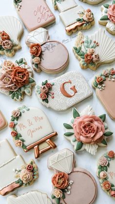 many decorated cookies on a white table with pink and orange flowers in the middle one cookie has an i love you written on it