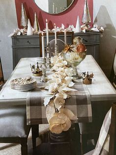 a dining room table is set with dishes and candles