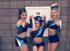 three cheerleaders posing for the camera in front of a fire hydrant with their hands up