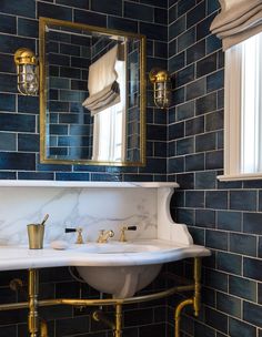 a white sink sitting under a mirror next to a gold faucet in a bathroom