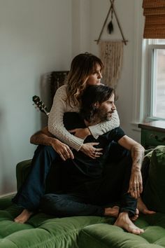 a man and woman sitting on top of a green couch