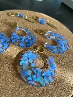 three pieces of blue glass sitting on top of a wooden table next to gold chains