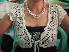 a woman sitting in front of a computer desk wearing a white lace top and pearl necklace