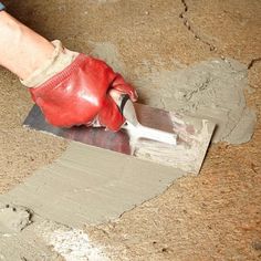 a person using a trowel to put cement on the floor in preparation for painting