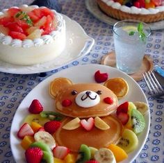 a plate topped with pancakes covered in fruit and a teddy bear face on top of it