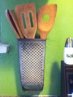 some wooden spoons and spatulas in a metal container on a counter top