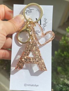 a person holding a keychain with a letter shaped like a heart on it