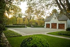 a house with a tennis court in the front yard and landscaping around it is surrounded by trees