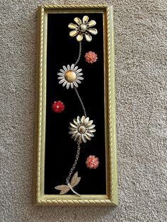 a framed painting with flowers and ladybugs on the wall next to a carpet