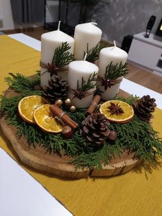 a table topped with candles and oranges on top of a wooden tray filled with pine cones