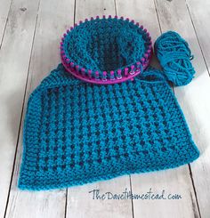 a blue crocheted hat with a purple ball of yarn sitting on top of it