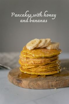 a stack of pancakes with bananas on top and syrup pouring down the middle, sitting on a cutting board