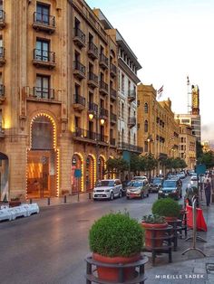 a city street filled with lots of cars and people walking down the sidewalk next to tall buildings