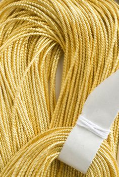 a white piece of cloth is on top of a yellow rope that has been braided together