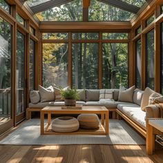 a living room filled with lots of furniture next to a large glass wall covered in trees