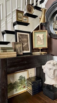 there are many framed pictures on the wall next to a stair case and busturine