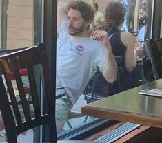 a man with dreadlocks sitting at a table in front of a glass door