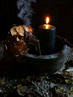 a lit candle sitting in a bowl filled with leaves