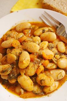 baked giant bean beans in a white bowl with a fork and bread on the side