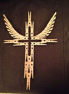 a cross made out of wooden sticks with wings on it's sides and the center