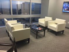 a living room filled with white furniture next to large windows and a flat screen tv mounted on the wall