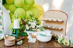 a table topped with cake and cupcakes next to a wall covered in balloons