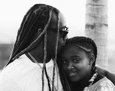 a black and white photo of a woman hugging a man with dreadlocks on his head