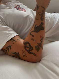 a tattooed man laying on top of a bed