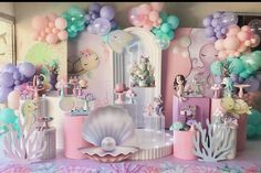 a room filled with lots of balloons and mermaid themed decorations on the walls, along with little mermaid figurines