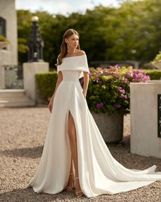 a woman in a white wedding dress posing for the camera with her legs slited