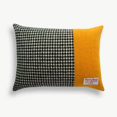 a black and white pillow with an orange patch on the side, sitting against a white background