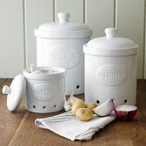 three white canisters sitting on top of a wooden table next to an apple