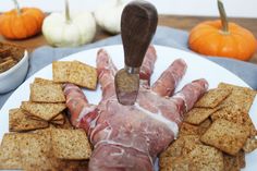 a white plate topped with crackers and meat on top of it next to pumpkins