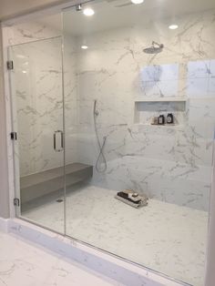 a bathroom with a glass shower door and white marble counter tops, along with a phone on the floor