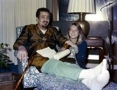 a man sitting next to a woman on top of a couch