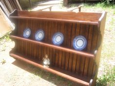 a wooden shelf with three blue plates on it and a small teddy bear in front