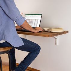 a person sitting at a desk with a laptop and book on their lap top computer