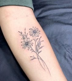 a woman's arm with daisies and leaves tattooed on the left side of her arm