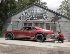 a red car parked in front of a building with an advertisement on it's side